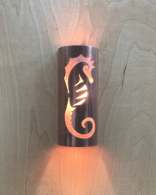 Copper sconce light in a half round shape with a seahorse design cut out